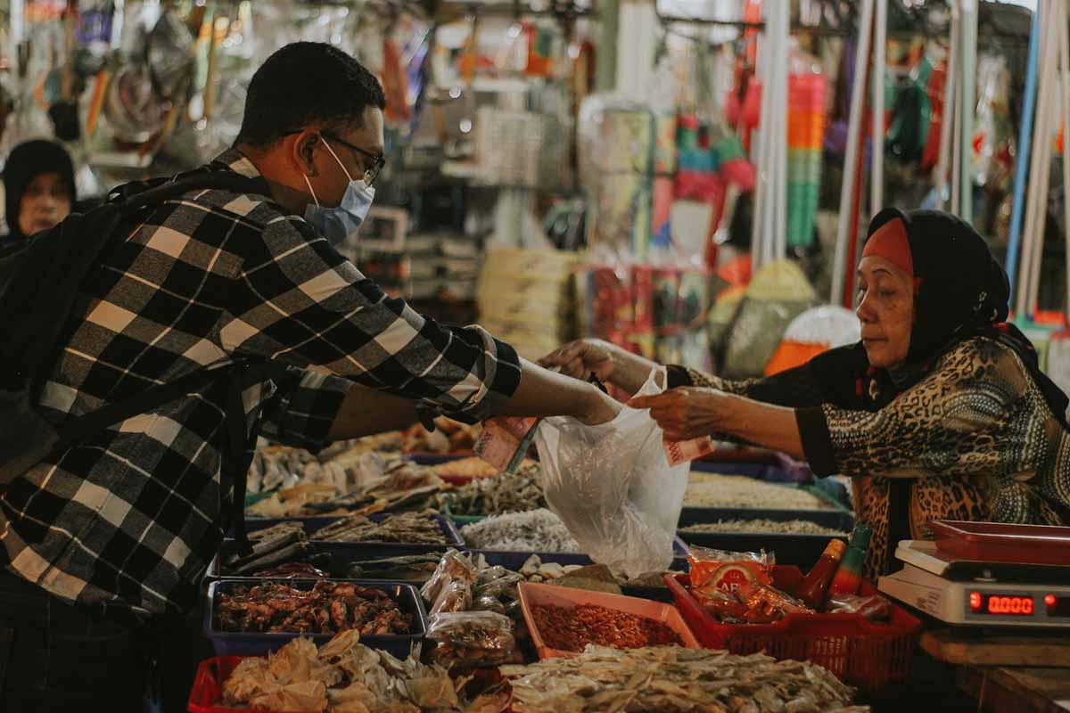 Pedagang dan pembeli sedang bertransaksi di sebuah pasar (Foto Fisipol UGM)